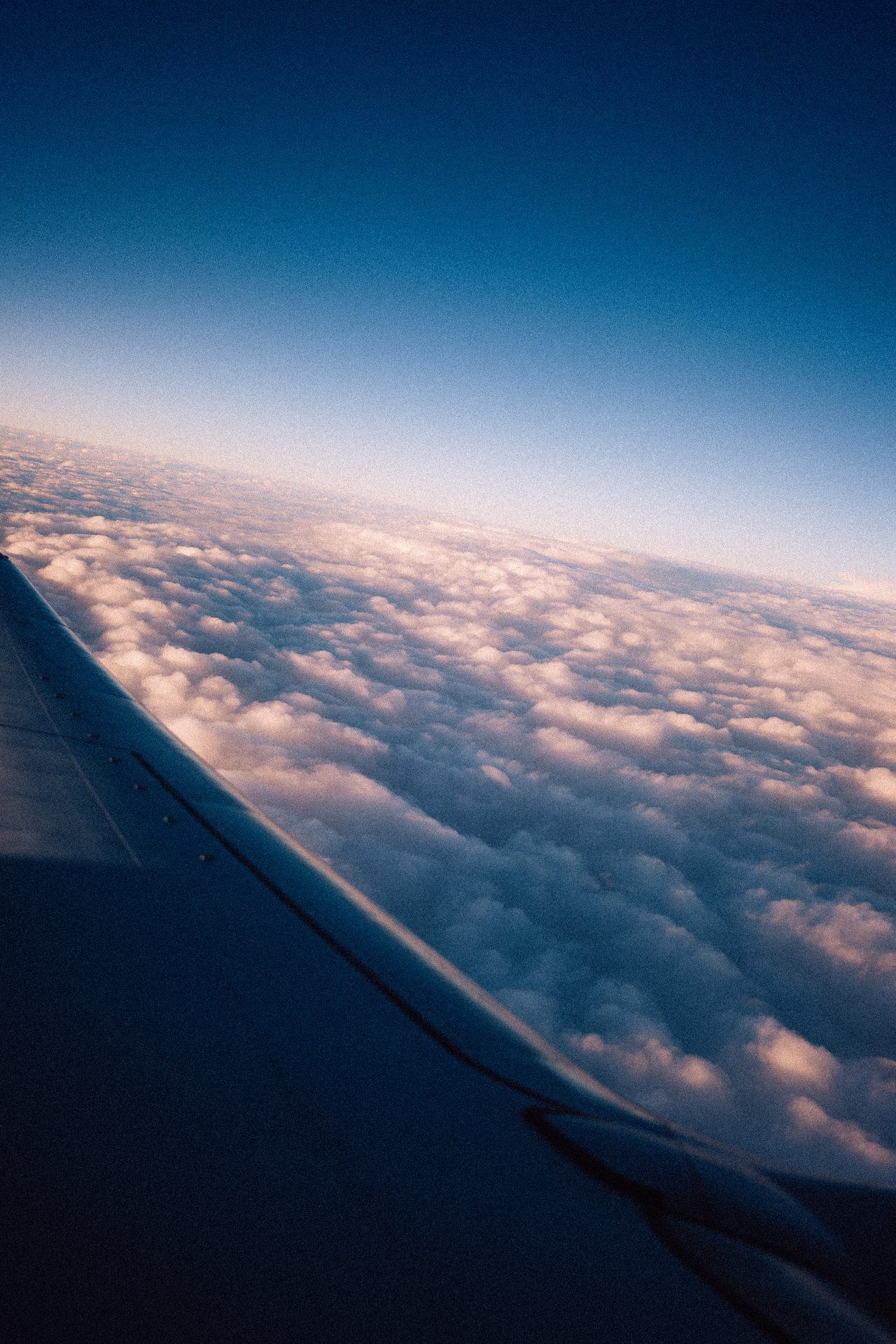 View over an airplane wing to clouds in the morning light