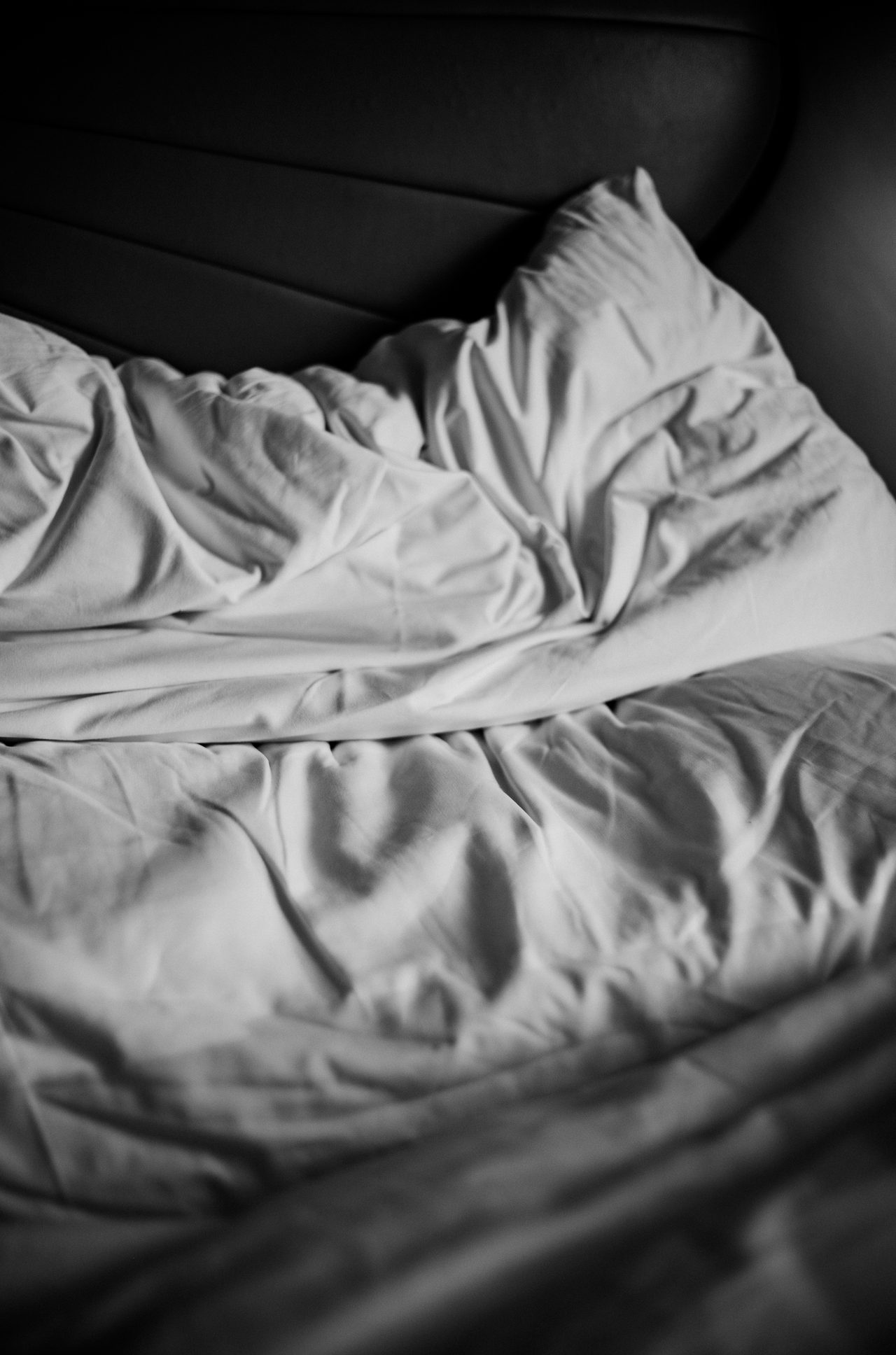 Unmade bed in morning light in black and white