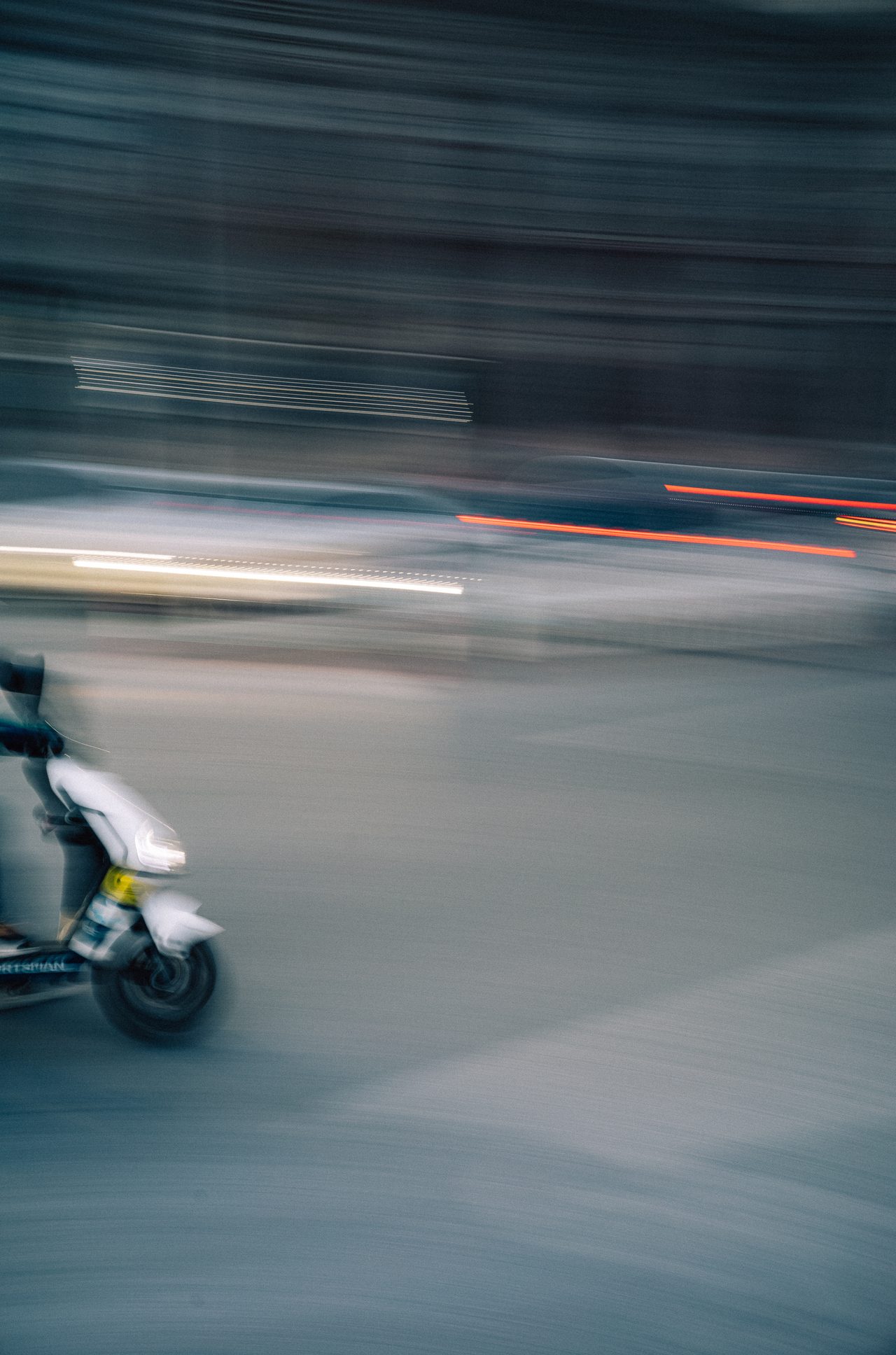 Motor scooter streaking through a nighttime street in a motion study