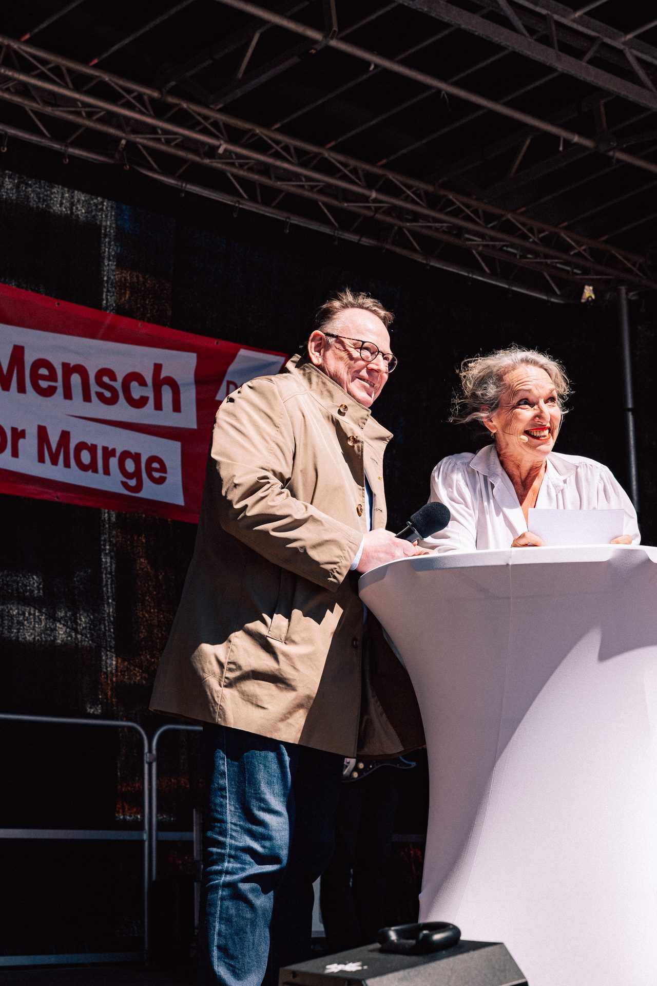 Two speakers laughing together at a podium on stage